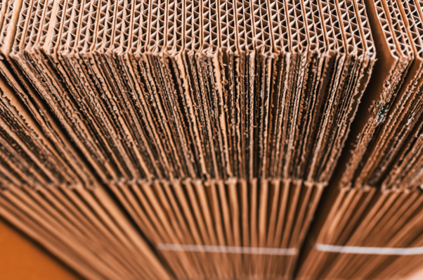 Stacked corrugated cardboard sheets used by a corrugated box manufacturer to create protective transit packaging.