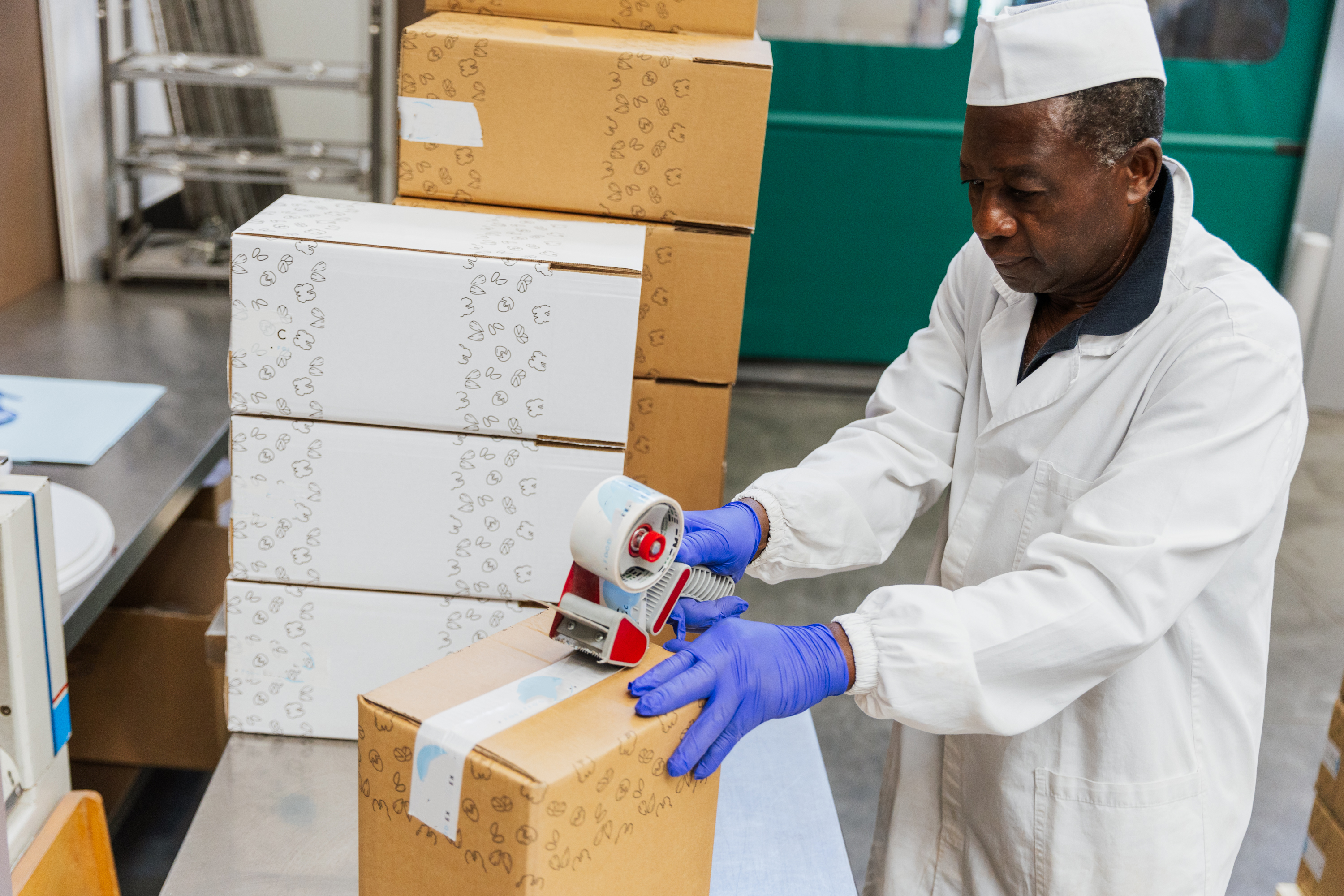 Warehouse worker in protective coat and gloves taping a box supplied by reliable packaging box manufacturers.